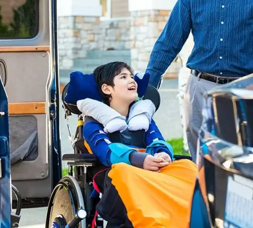 Special needs eleven year old boy in wheelchair outdoors ready to ride on the vehicle wheelchair lift with father